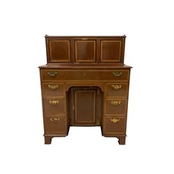 Edwardian mahogany kneehole secretaire desk, with satinwood crossbanding bordered with ebony and boxwood stringing, the rectangular top with cavetto gallery, rectangular detachable structure with central fall front door enclosing two satinwood fronted l drawers, flanked by panel doors enclosing pigeonholes, the projecting base with long fall front frieze drawer with inset writing surface, above six graduating drawers with central cupboard, raised on square feet with casters, stamped Collmann & Scantlebury