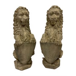 Pair cast stone seat lions, each holding shield, on canted rectangular plinths