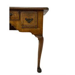 George II walnut lowboy, the rectangular top with boxwood and ebony stringing and moulded edge, fitted with a short central drawer flanked by two deeper drawers, each with foliate decorated brass plates and drop handles, the shaped and arched apron with cock-beaded lower edge, raised on cabriole supports terminating in pad feet