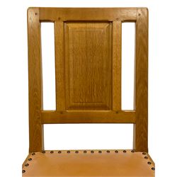 Knightman - set of four oak dining chairs, fielded panelled back over seat upholstered in tan leather with stud work, on octagonal front supports united by stretchers, by Horace Knight, Balk, Thirsk 