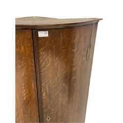 Early 19th century oak bow fronted corner wall cupboard, two doors enclosing three shelves