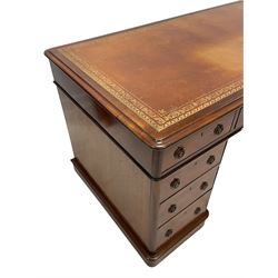 Victorian mahogany twin pedestal desk, moulded rectangular top with rounded corners, tan leather inset writing surface with gilt borders, fitted with nine drawers, each with circular pierced and press brass handle plates and loop handles, raised moulded plinth base