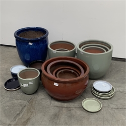 Twelve glazed terracotta plant pots, (D45cm Max) and twelve plant pot plates of varying size and colour.  