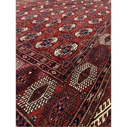 Persian Bokhara red ground carpet, with gul motif on central field and stylised geometric design to border324cm x 225cm