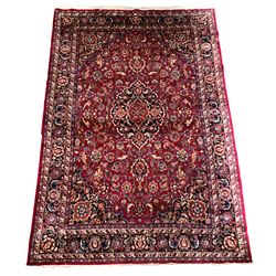 Persian Meshed red and blue ground carpet, floral medallion on busy red field enclosed by border 252cm x 363cm