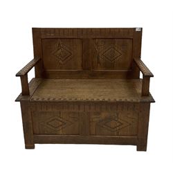 20th century oak settle, carved with lozenges and hinged seat, raised on stile supports 