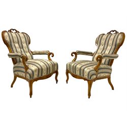 Pair of Victorian walnut drawing room armchairs, pierced shaped resting rail, the buttoned back and sprung seat upholstered in blue and ivory floral patterned fabric, the scrolled arm terminals over a shaped apron, raised on cabriole front supports