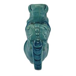 Burmantofts Faience turquoise-glaze ewer modelled as a grotesque hound, seated on all fours, with tilted head and mouth agape in a howl, impressed factory marks beneath, model no. 555 H33.5cm 