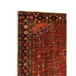 Persian Zanjan red ground rug, the central medallion with panels of stylised tree of life motifs, within a busy field of Herati motifs and matched spandrels, the dark indigo border with eight-pointed star motifs in alternating colours