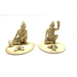  Pair of late 19th/early20th Century Indian carved ivory seated figures of street hawkers on circular bases H4.5cm