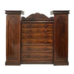 Victorian double wardrobe, the scrolled cornice over six graduated drawers, flanked by two doors, opening to reveal interior fitted for hanging, raised on a plinth base 