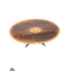 Reproduction Regency design mahogany coffee table, the oval satinwood cross banded top centred with floral inlay, over turned column and four splayed supports terminating in hairy paw brass cup castors, 121cm x 69cm, H51cm