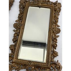 Pair of Victorian patinated cast iron wall mirrors, circa 1893, each of upright rectangular form with pierced and scrolled frames, surmounted by a Cherub mask with scroll supports and bevelled glass plates, H47cm x W27cm