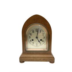 German - early 20th century 8-day oak cased striking mantle clock, striking the hours and half hours on a coiled gong, in a lancet shaped case raised on bun feet, with a slivered sheet dial, arabic numerals, minute track and steel spade hands. With key and pendulum.