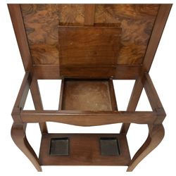 Early 20th century walnut hallstand, raised back with rectangular bevelled plate over double figured panels, surrounded by coat hooks, fitted with single hinged glove box, the undertier with twin inset umbrella drip trays, united by cabriole supports