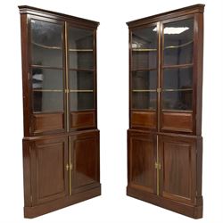 Matched pair of mahogany corner cabinets, projecting dentil cornice over glazed and panelled doors, the lower section enclosed by double panelled doors, on plinth base, one cabinet being George III period and the other reproduced to match 