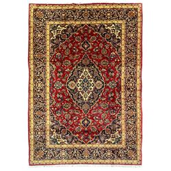 Persian Kashan red ground rug, blue central medallion and spandrels with floral design, the field decorated with scrolling branch and stylised plant motifs, repeating border with guards