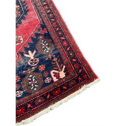 Persian Hamadan crimson ground rug, the field decorated with geometric and stylised plant motifs, the main border decorated with flower heads within geometric guard stripes 