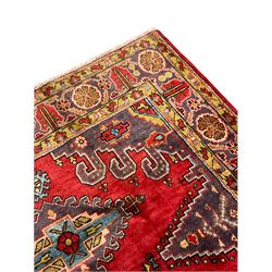 Persian red ground rug, the field decorated with stepped lozenges and central medallion, guarded border with stylised flower head motifs 