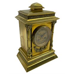 Brass cased eight-day French mantle clock c 1910, with a stepped pediment and applied decorative frieze, recessed reeded pillars to the front of the case on a conforming stepped plinth with a canted base, gilt dial with a pierced circular boss to the centre, cameo Arabic numerals and steel fleur di Lis hands, striking movement, striking the hours and half hours on a coiled gong. With pendulum and key.   