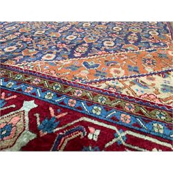 Persian Herati blue and red ground rug, the central medallion and surrounding field decorated with repeating Herati motifs, rust ground spandrels decorated with small stylised motifs, flowerhead design guard bands enclosing the band decorated with stylised plant motifs, thick woollen pile