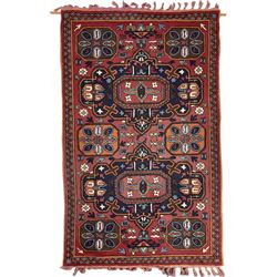 Caucasian design crewelwork hanging, red ground decorated with two central indigo medallions surrounded by geometric designs 