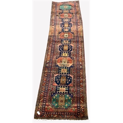 Large Persian Karajeh red ground runner, eight lozenges in green blue and red, decorated with geometric patterns on a red field, guarded boarder with repeated floral and geometric motif, 430cm x 112cm