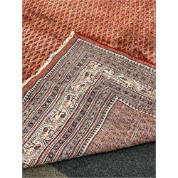 Large Persian Arak red ground carpet, the central field with repeating motif, enclosed by geometric border 360cm x 352cm
