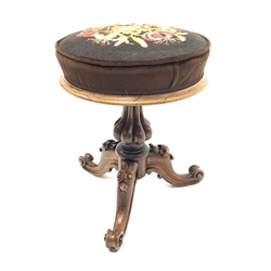 Early Victorian rosewood revolving adjustable piano stool, cushioned seat upholstered in floral needlework cover, lobe carbed baluster column support, three out splayed flower head and foliage carved supports with scroll carved terminals, D38cm