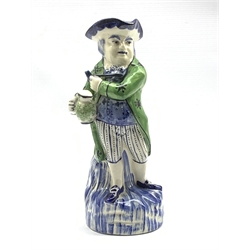 Continental Toby jug modelled as a standing figure wearing a green coat holding a jug of ale and a clay pipe, monogram to base H29cm 