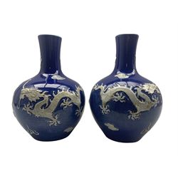 Pair of Yuan style Chinese blue glazed bottle shaped vases each decorated in high relief with dragons amidst cloud and flame scrolls, bearing Yung-Cheng mark beneath H31cm 