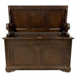 Mid 20th century oak Monks bench, the panelled metamorphic top over box seat with hinged lid, the arm rests carved in the shape of lions, the front carved with lunettes and fluted columns, on bracket feet