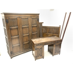 Early 20th century oak bedroom suite, comprising triple wardrobe with dentil cornice over three drawers enclosing interior fitted with shelves and for hanging, (W157cm, D54cm, H182cm) a double bed with lunette and linen carved headboard and vono rails (W137cm) and a dressing table, fitted with three drawers and two cupboards, (W125cm)