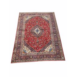 Hand knotted Iranian Kashan red ground carpet, busy red field centred by floral medallion of blues and ivory 390cm x 300cm
