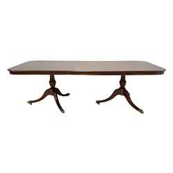 Regency style twin pillar mahogany dining table, the flat top with inlay, raised on turned columns, leading into triple splayed supports terminating in brass hairy paw castors (W245cm, H77cm, W115cm) comes with one additional leaf