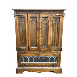 Old Charm - 20th century oak Hi - Fi / record cabinet, fitted with two bi fold doors carved with gothic arches over lead glazed fall front door under, raised on skirted base W71cm, H97cm, D49cm