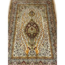 Fine silk Persian Hereke rug, the mihrab enclosing flower heads and interlacing tree branches, central floral medallions, multi-band guarded border decorated with stylised plant motifs and geometric designs, with signature panel 
