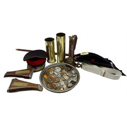 Collection of militaria including two Glengarries, peaked cap, military belt, two shell casings, badges and buttons, button polisher, wrist band, two butt cribbage markers, bugle and swagger stick