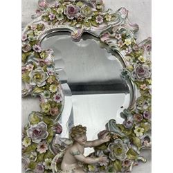 Pair of Ruldolstadt Volkstedt porcelain wall mirrors, scroll form with bevelled glass plates, the frames encrusted with flowers and Putti,  H49cm x W31cm