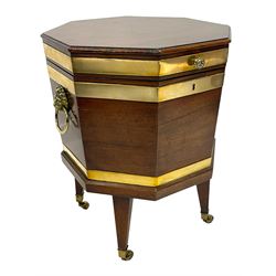 George III mahogany and brass bound octagonal cellarette on stand, hinged lid enclosing fitted interior, with twin brass lion mask mounts and ring handles, the lower moulded edge over square tapering supports with brass cups and castors
