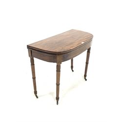 George IV mahogany fold over card table with ebonised stringing, raised on ring turned supports terminating in brass cup castors, W91cm, H75cm, D45cm