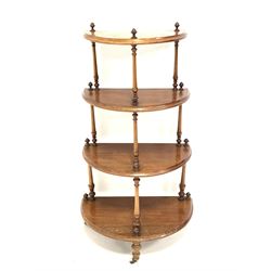 Victorian walnut demi lune whatnot, with four graduated tiers raised on spindle supports, terminating in brass and ceramic castors H103cm
