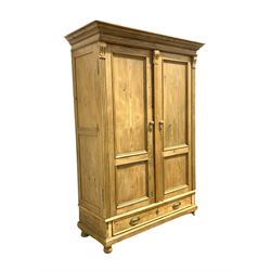 Late 19th century pine wardrobe, two fielded panelled doors enclosing interior fitted for hanging, drawer under, raised on bun supports W135cm, H191cm, D59cm