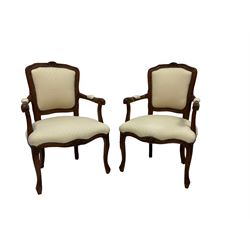 Pair Louis XVI design walnut framed salon armchairs, the cresting rail decorated with moulded flowerheads and extending fluting, scrolled arm terminals, raised on cabriole supports, upholstered in ivory patterned fabric with studwork, 
