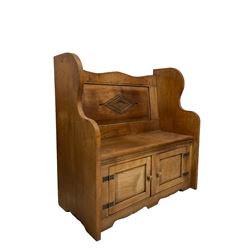Oak and elm settle, the panelled back with carved lozenge over seat and two cupboard doors, raised on panel end supports 