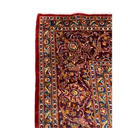 Persian Kashan red ground carpet, the central floral pole medallion within a busy field filled with with scrolling foliate decoration and stylised palmettes, with matching spandrels, the guarded border with interlaced scrolling floral motifs