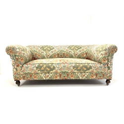 20th century drop arm chesterfield two seat sofa, upholstered in floral linen, and raised on  front bun supports and castors, W188cm