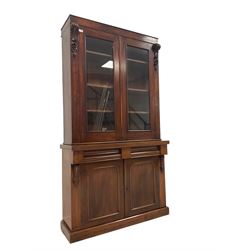 Late 19th century mahogany bookcase, fitted with two glazed doors enclosing three adjustable shelves, flanked by scrolled corbels with acanthus decoration, lower section fitted with two drawers over two panelled cupboard doors, raised on plinth base