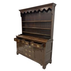19th century Georgian design oak dresser, projecting cornice over shaped apron and three-tier plate rack, the base fitted with three cock-beaded frieze drawers over three central faux drawers, flanked by panelled cupboards, lower moulded edge over bracket feet