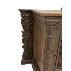 18th century carved oak cupboard, enclosed by panelled door carved with central bird motif and scrolled leafage with an outer ebony band, the frieze and uprights carved with repeating lunette and floral designs, flanked by scrolled foliate carved upright brackets